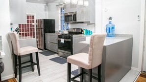 A modern kitchen with stainless steel appliances, a water dispenser, and two bar stools. - Luxury Home away from Home (Georgetown)
