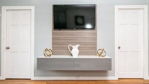 A room with a grey console table, a white pitcher, and two gold decorative items. - Luxury Home away from Home (Georgetown)