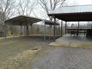 Relax under the shelter, surrounded by trees, with a table and chairs for dining or socializing.