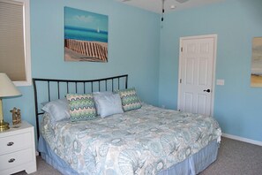 Un dormitorio con una cama, una mesita de noche, una puerta y un cuadro en la pared.
