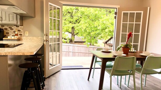 A kitchen with a large window, a dining area with chairs, and a bar stool area. - •The Book Nook• Books•Arcade•Grill•Workspace! (North Richland Hills)