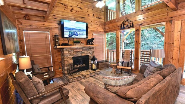 A cozy cabin interior with a stone fireplace, wooden furniture, and a television mounted on the wall. - Rustic CreekSide Memories/5min>PForge-GBurg/HotTub (Pigeon Forge)