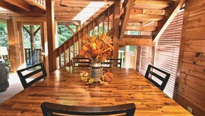A wooden dining table with chairs, a vase with autumn leaves, and a pumpkin centerpiece. - Rustic CreekSide Memories/5min>PForge-GBurg/HotTub (Pigeon Forge)