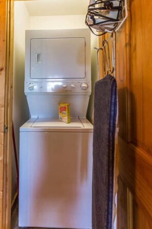 A compact laundry room with a washing machine and dryer, a towel rack, and a detergent box on the dryer. - Breathtaking MtnCity View/HotTub/5min->PForge Pkwy (Sevierville)