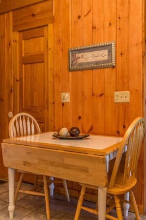 A wooden dining table with two chairs, a framed certificate on the wall, and a plate with two eggs on the table.