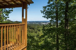 A wooden deck with a view of a forested area and a distant town.