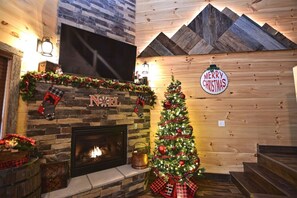 Ein gemütlicher Kaminbereich mit Weihnachtsbaum und festlicher Dekoration.