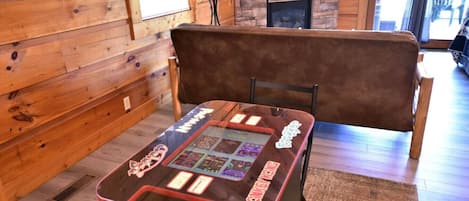 Un intérieur en bois avec une table de jeux, un banc et une cheminée.