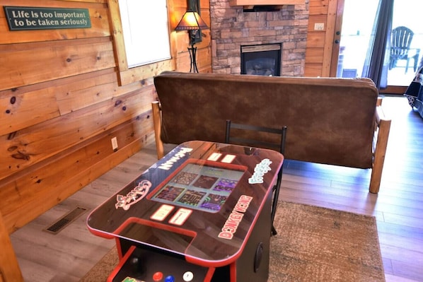 A wooden interior with a table game, a bench, and a fireplace.