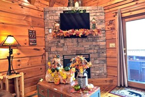 A cozy room with a stone fireplace, autumn decorations, and a wooden interior.