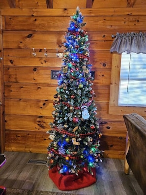 A Christmas tree decorated with ornaments and lights, placed in a wooden room with a sign reading "Life to".