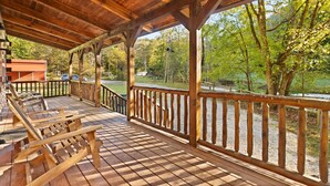 A wooden deck with benches, a railing, and a view of a forested area.