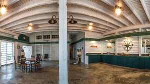 A spacious room with a high arched ceiling, wooden walls, and a central dining table with chairs. - Dock House Guest Suite (Belhaven)
