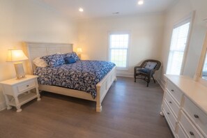Cozy retreat with a large bed, nightstand, and dresser, plus a comfortable chair for relaxation.