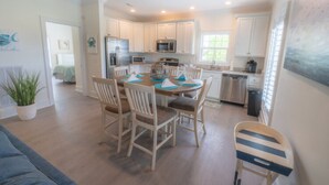 A modern kitchen with white cabinets, a dining table with chairs, and a small island.
