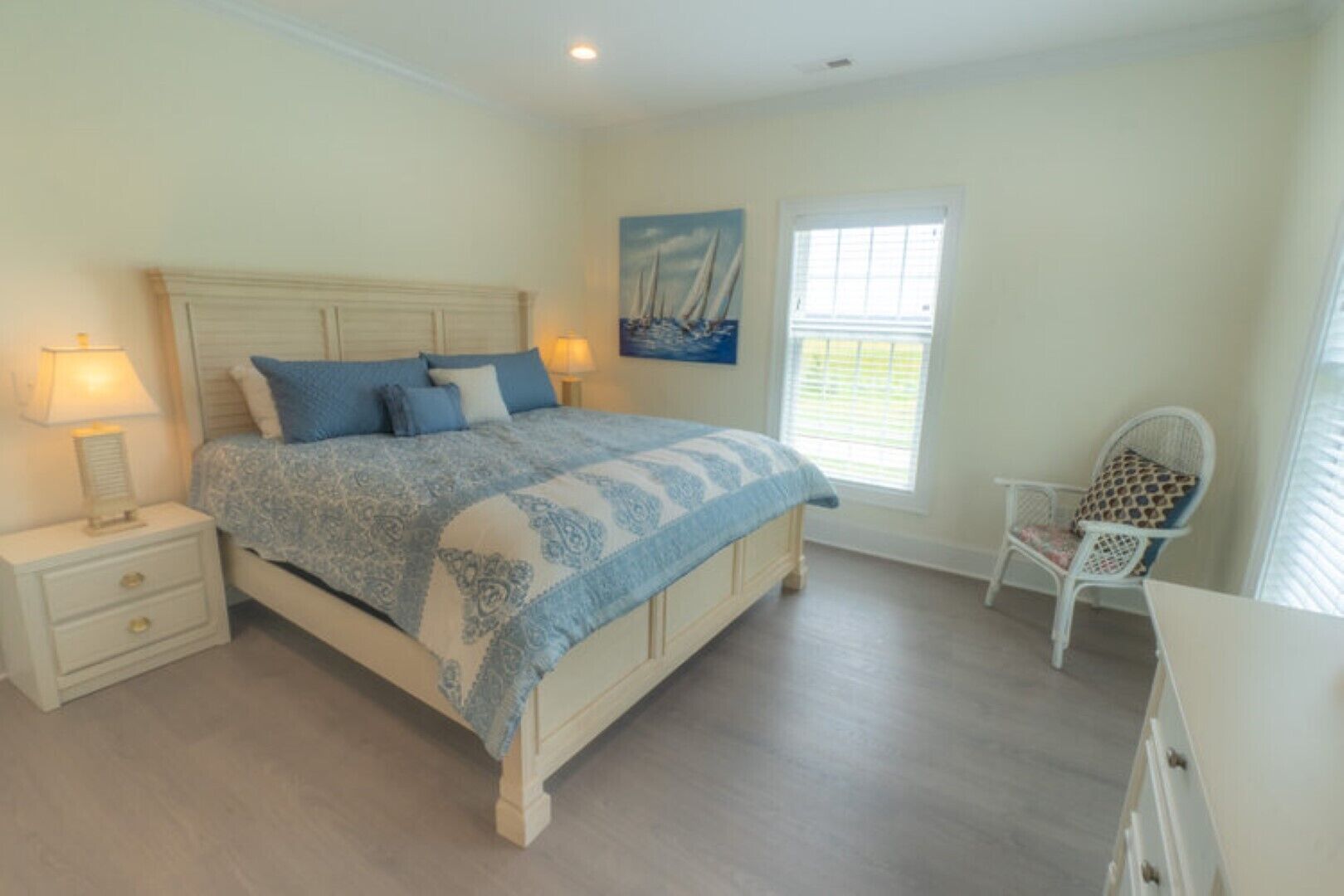 A bedroom with a bed, nightstands, a chair, and a window.