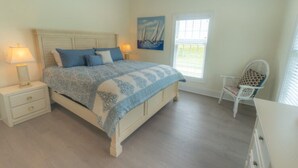 A bedroom with a bed, nightstands, a chair, and a window.