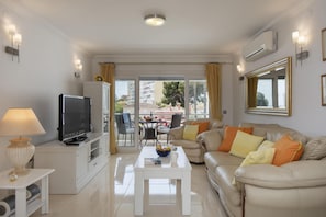 Relax in this stylish living room with a flat-screen TV, comfortable sofa, and sliding glass door to an outdoor dining area.