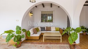 A cozy outdoor seating area with a sofa and a coffee table, surrounded by potted plants.