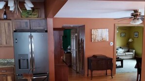 Une cuisine dotée d’un plan de travail en granit, d’un réfrigérateur en acier inoxydable, de meubles de rangement en bois et d’un ventilateur de plafond.