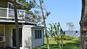 Une maison à deux étages avec un balcon, une pelouse et une vue sur l’eau.
