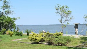 Un jardin aménagé avec une statue, un bassin et une vue sur la étendue d’eau.