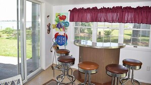 Une cuisine dotée d’une grande fenêtre, d’un coin bar avec des tabourets et offrant une vue sur l’extérieur.