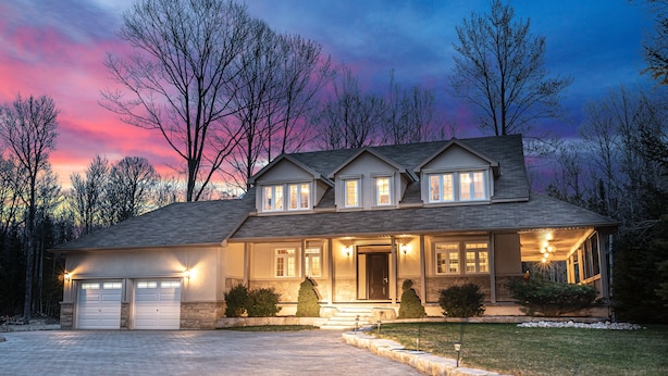 A two-story house with a driveway, garage, and a well-lit front porch. - Big Beautiful Georgian Bay Family Cottage (Tiny)