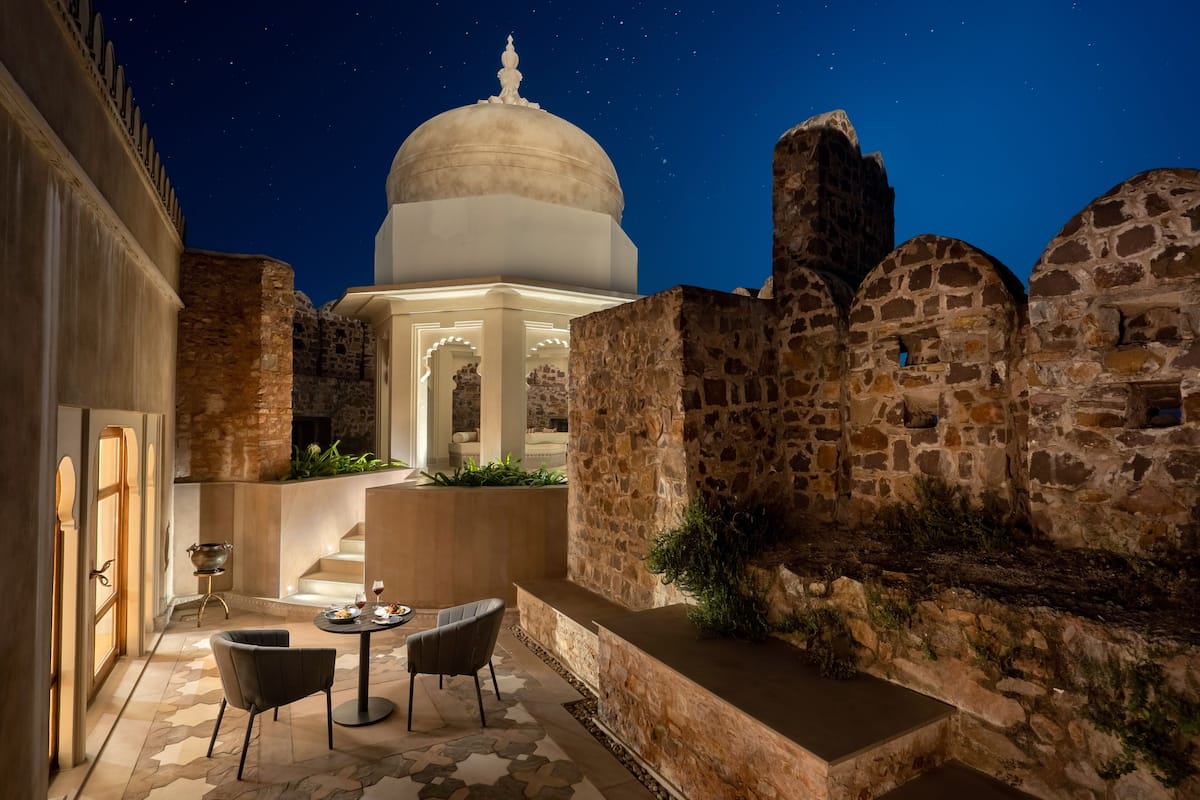 A courtyard with a stone wall, a white dome structure, and a seating area with a table and chairs.