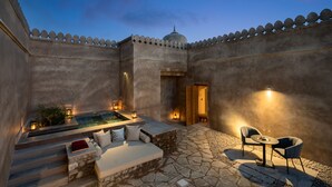A serene outdoor seating area with stone steps, a small pool, and a dining table with chairs. - Six Senses Fort Barwara (Chauth Ka Barwara)