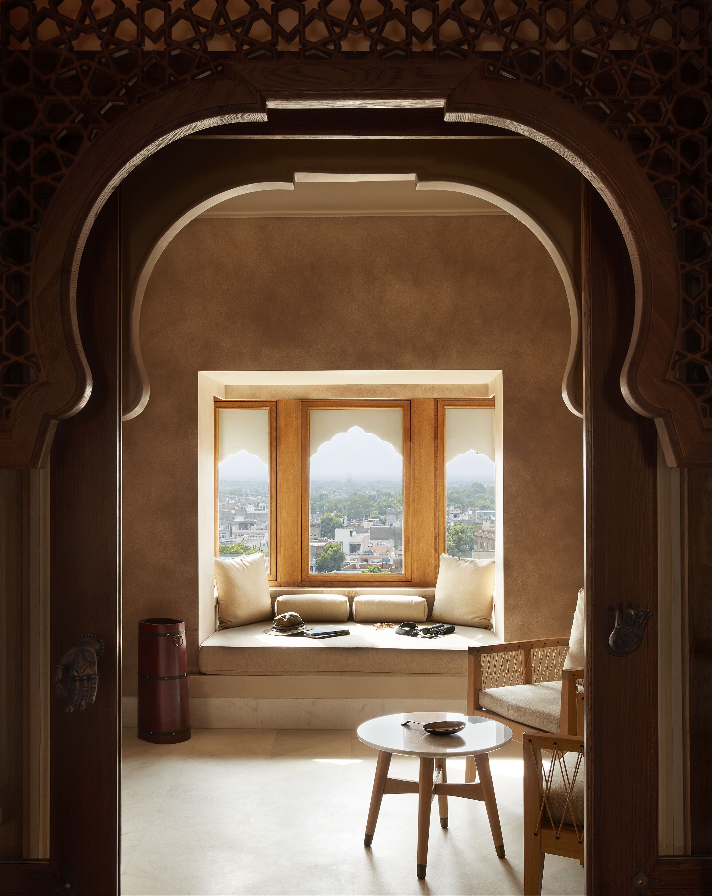 A room with a window seat, a round table, and a chair.