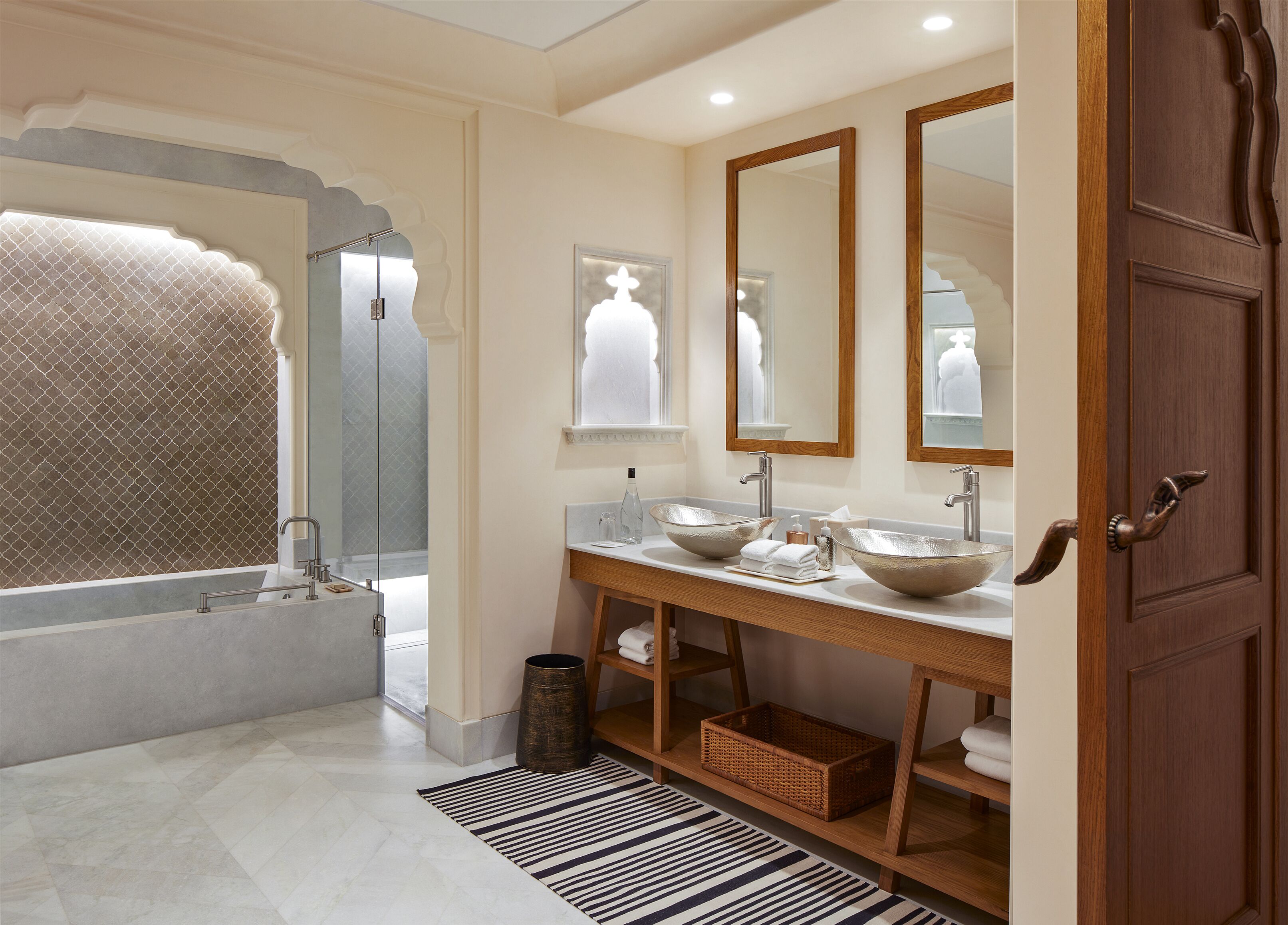 A bathroom with a bathtub, two sinks with large bowls, a mirror, and a wooden vanity.