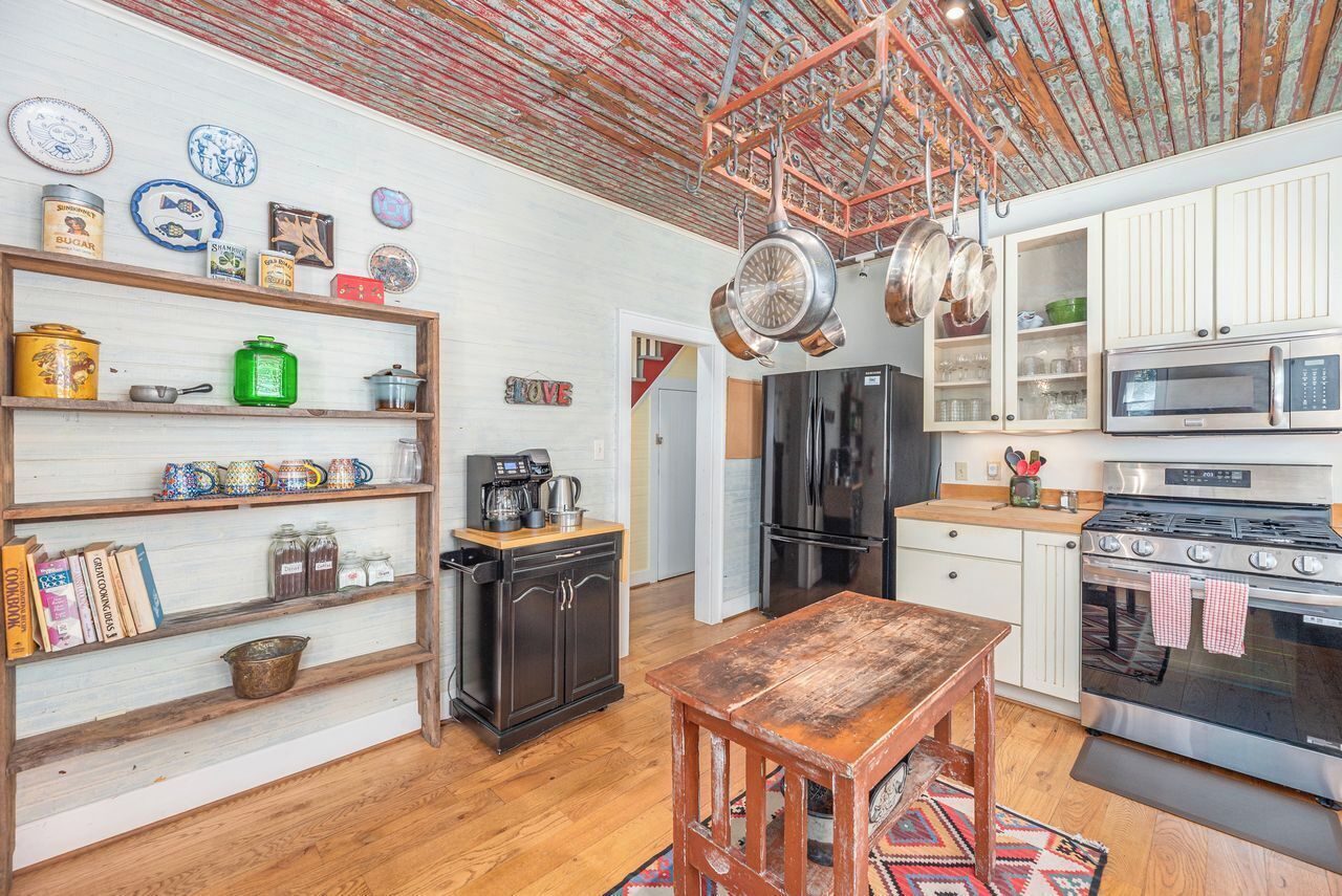 A kitchen with wooden shelves, a coffee machine, a refrigerator, and a stove.