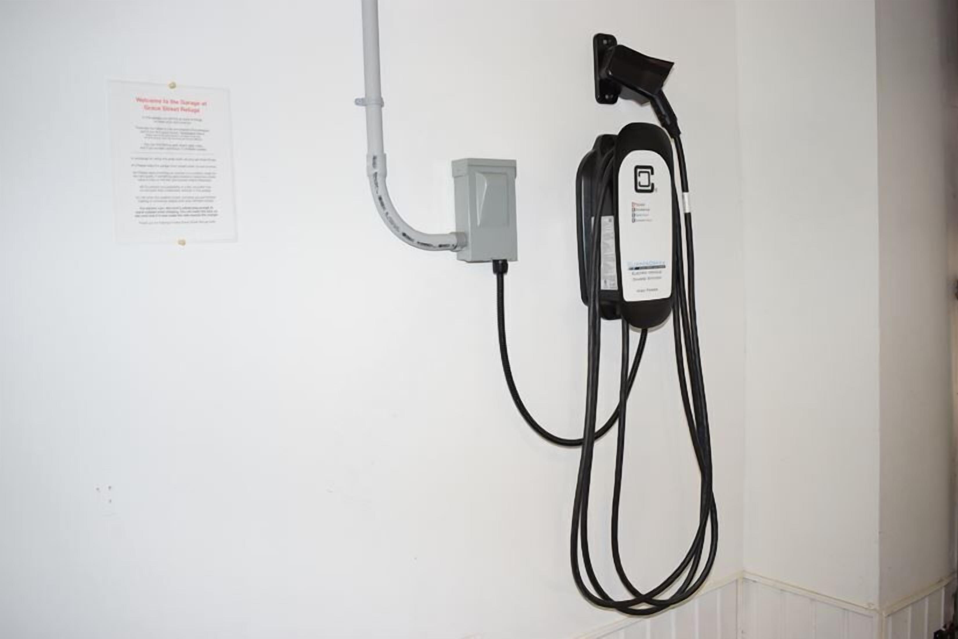 Eine Wandsteckdose mit einem an ein Kabel angeschlossenen Gerät, einem Hinweis und einer Kabelrinne.
