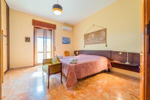 A bedroom with a bed, a chair, a desk, a lamp, and a painting on the wall.