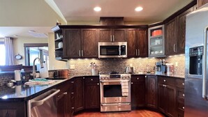 A modern kitchen with dark wood cabinets, stainless steel appliances, and a brick backsplash. - Rs156 Downtown Whitefish Experience (Whitefish)