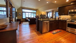A spacious kitchen with wooden flooring, dark cabinetry, and stainless steel appliances.