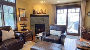 A cozy living room with leather sofas, a fireplace, and a view of the outdoors. - Rs156 Downtown Whitefish Experience (Whitefish)
