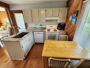 Una cocina compacta con lavavajillas integrado, estufa y comedor con mesa y sillas de madera.