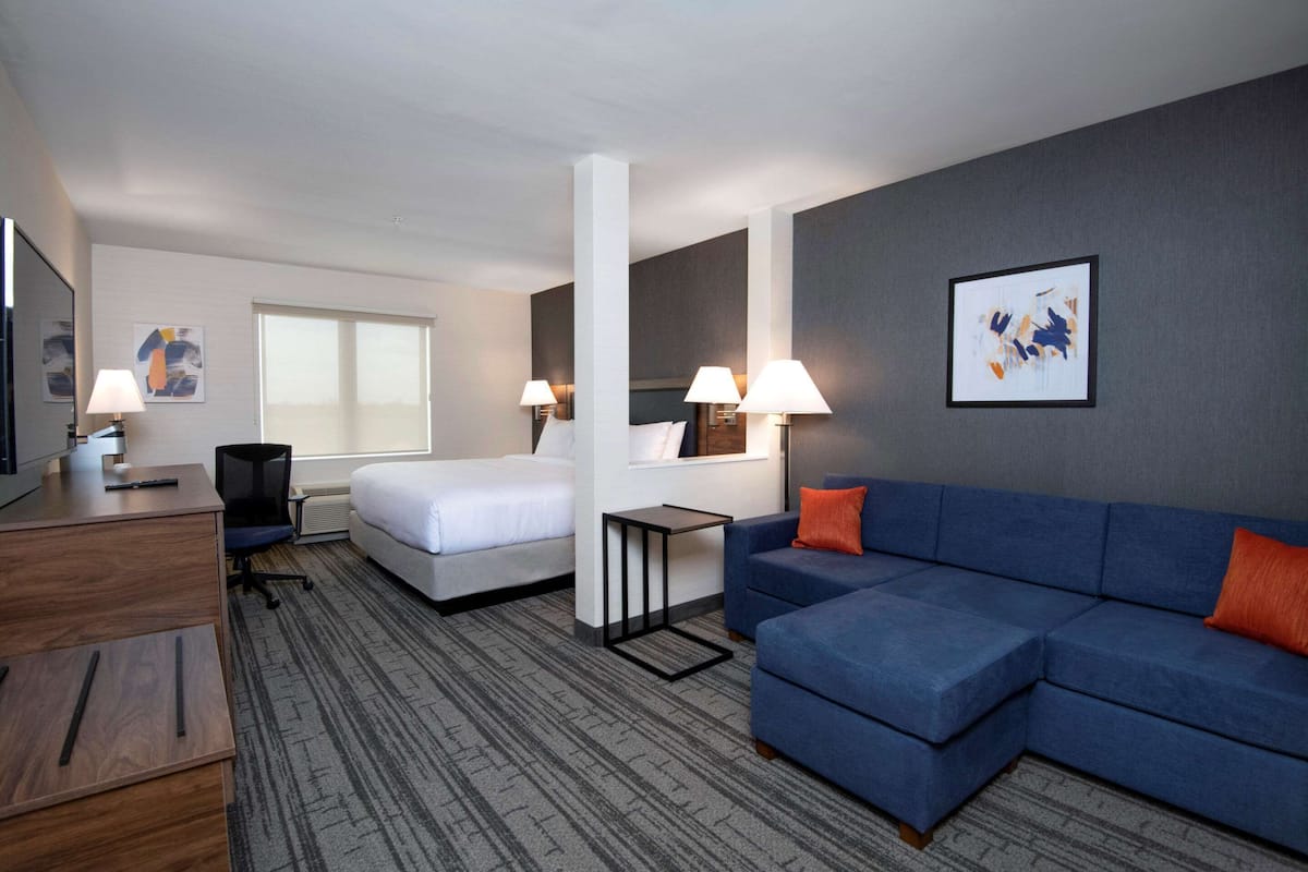 Ein Hotelzimmer mit Bett, blauem Sofa, Schreibtisch und Stuhl.