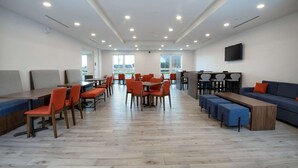A spacious indoor area with multiple seating arrangements, including tables and chairs, and a large sofa. - Comfort Inn & Suites (Carleton Place)