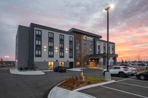 Un hotel Comfort Inn & Suites con un diseño moderno, que cuenta con un estacionamiento y un cielo despejado al atardecer.