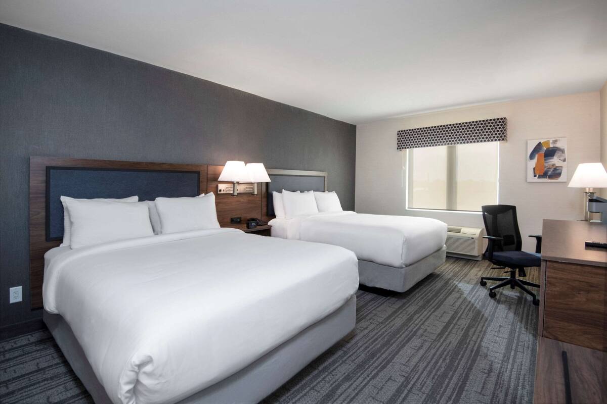 Ein Hotelzimmer mit zwei Betten, einem Schreibtisch und einem Stuhl.
