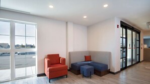 A modern waiting area with a sofa, armchair, and ottoman. - Comfort Inn & Suites (Carleton Place)
