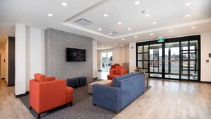 A lobby with seating areas, a flat-screen TV mounted on the wall, and a glass door entrance. - Comfort Inn & Suites (Carleton Place)