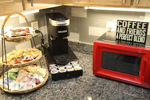 A coffee machine, a microwave, and a basket of coffee pods on a kitchen counter. - Huge SouthPark 2Br/2Ba w Patio Come Laugh Live Love here ❤ ❤ (Charlotte)