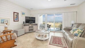 A living room with a TV, seating, and a view to the outside.