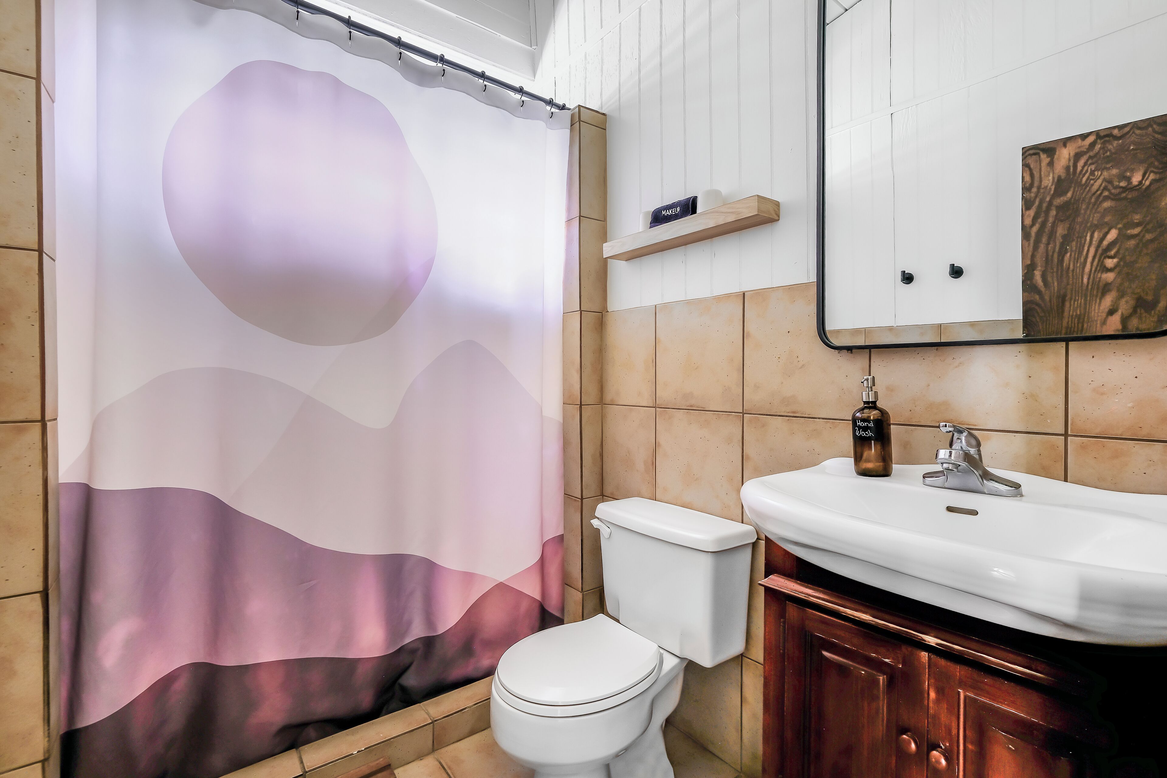 A bathroom with a toilet, sink, and a shower curtain with a wave design.
