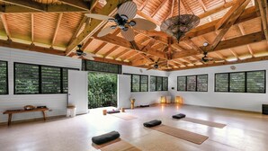 A spacious room with wooden beams, large windows, and exercise mats. - Casa Grande Mountain Retreat - Adults Only (Utuado)