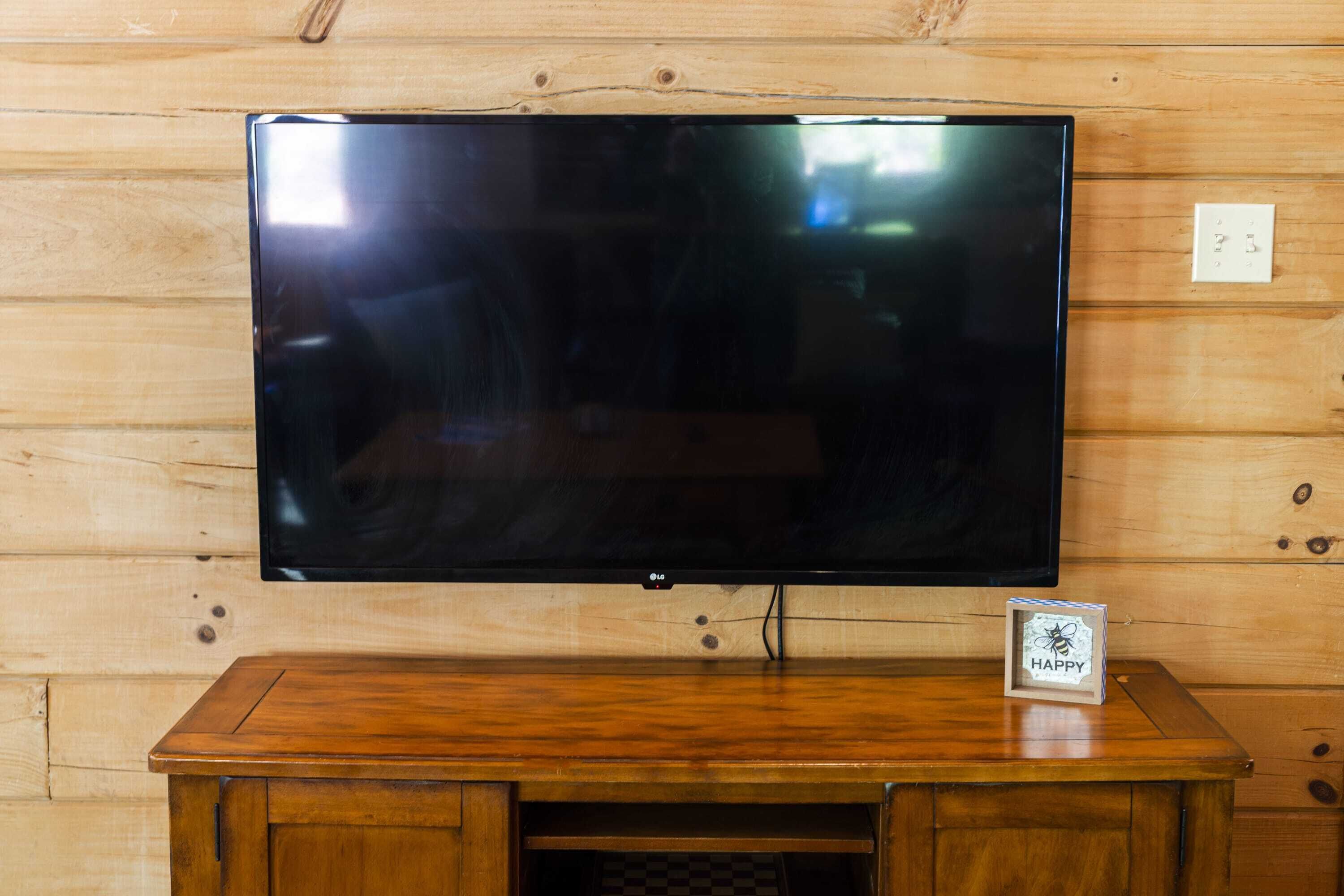 Et fladskærms-tv ophængt på en trævæg, med et lille bord under.